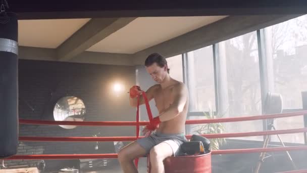 Attractive male boxer wrapping red bandages in the boxing club. — Stock Video