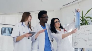 Üç çok ulusal hastanın akciğer tartışırken xray iş günü boyunca doktorlar..