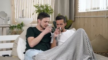 Beyaz gay çift evde yatakta yalan beyaz şarap içiyor. Eşcinsel ilişkileri kavramı