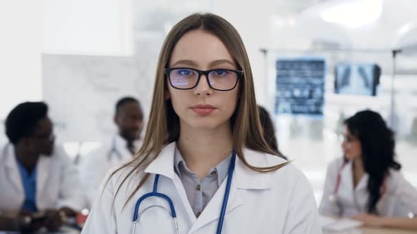 Primer plano de confianza caucásica médico femenino y equipo de personal en el fondo en el hospital . — Vídeo de stock