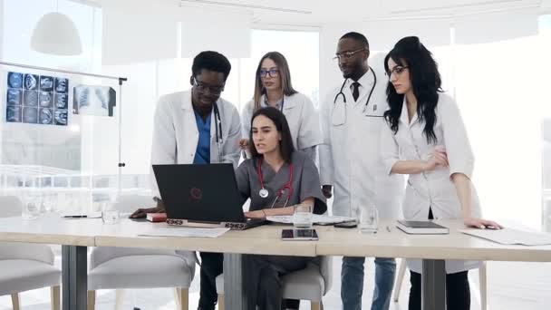 Vijf jonge artsen met laptop samen in het ziekenhuis. — Stockvideo