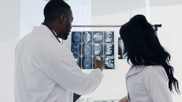 Dos doctores discutiendo huellas de rayos X de huesos de pacientes en el hospital . — Vídeos de Stock