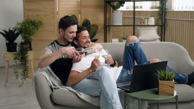 Eşcinsel çift, Eşcinsel insanlar, aynı eşcinsel evlilik beyaz erkekler arasında. Laptop yatakta film izlerken şarap içme mutlu gay çift