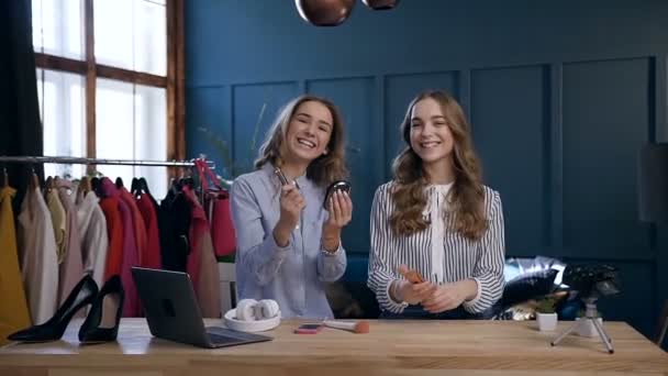 Dolly sköt av attraktiva två kvinnor possing till kameran med smink verktyg i händerna. — Stockvideo