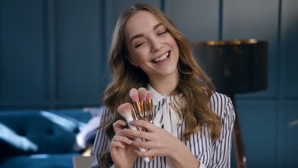 Happy cute Woman toepassing Blush op de jukbeenderen met behulp van roze penseel in de kamer. — Stockvideo