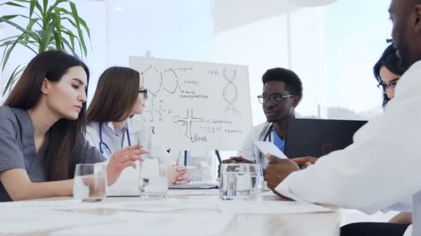 Grupo multiétnico de médicos profesionales con portátil en la reunión en el consultorio médico. Salud, hospital, profesionales, tecnología y medicina — Vídeos de Stock