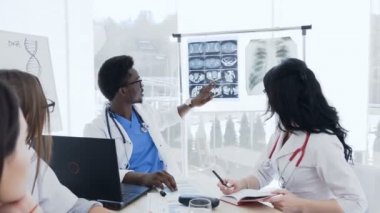 Hastanın x-ışını ile çok etnik profesyonel doktorlar grubu, hastanede hastalığın geçmişini görüşüyorlar ve tartışıyorlar. Hastane, Meslek, insan ve tıp konsepti