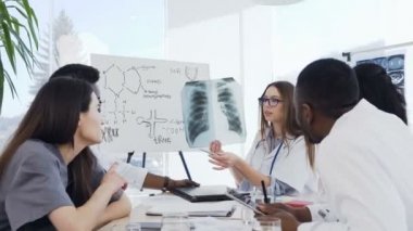 Klinikte konferans sırasında Hands x-ışını filmi tutan kadın doktor. Çok etnik grubun profesyonel doktorlar radyografi kabine hasta tutma analiz x-ışını akciğerleri incelemek