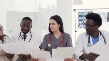 Modern hastanede konferans salonunda toplantı yapan çok ırklı genç doktorlar ekibi. Çok ırklı doktorlar grubu hastalık geçmişleri hastalar okuyan tıbbi okuyor