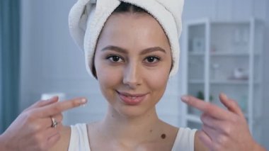 Genç çekici kadın portre elmacık kemikleri üzerinde yüz kremi uygulayarak.