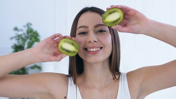 Portrait shot of hahsome young woman posing with two half of kiwi. — Stock Video