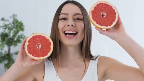Schöne junge Frau mit Grapefruit auf den Augen. — Stockvideo