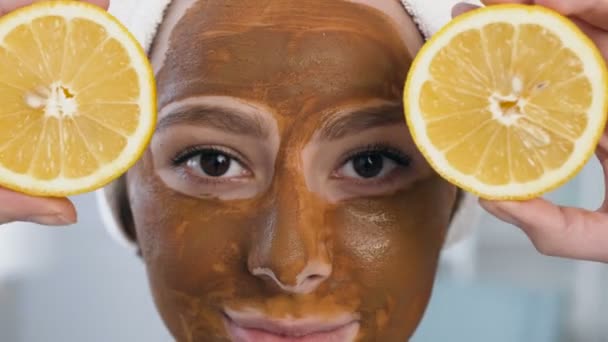 Närbild skott av söt kvinna poserar med två hälften av citron på ögonen med mask i ansiktet. — Stockvideo