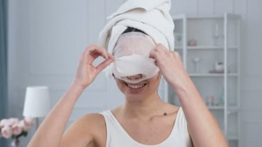 Genç güzel kadın yüz gençleştirici kozmetik beyaz doku maskesi kaldırma.