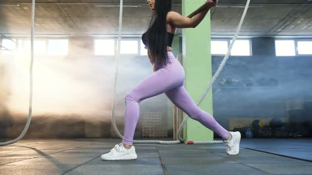 Mujer joven guapo en cuclillas para fortalecer las piernas y las nalgas durante el entrenamiento en el gimnasio . — Vídeos de Stock