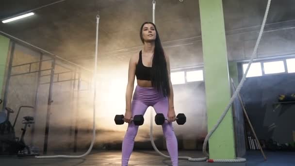 Fit caucasian woman squatting with dumbbells in the gym. — Stock Video