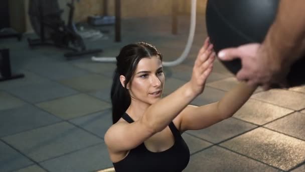 Belle femme sportive faisant des abdos exercice avec ballon d'aérobic avec entraîneur masculin . — Video