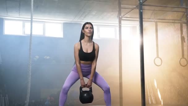 Snygg passform kvinna huk med Kettlebells i händerna i CrossFit gym. — Stockvideo