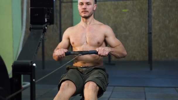 Starker junger Mann trainiert wieder am Sportsimulator im Fitnessstudio. — Stockvideo