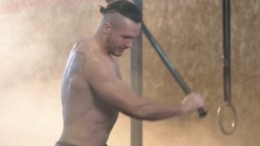 Yakışıklı genç adam spor salonunda crossfit eğitim sırasında çekiç kullanarak traktör binmek dayak yan görünümü.