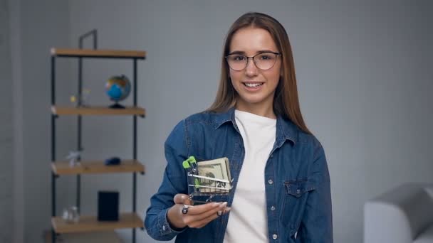 Portraitaufnahme einer attraktiven blonden Frau, die einen Einkaufswagen mit Geld in die Kamera reckt. — Stockvideo