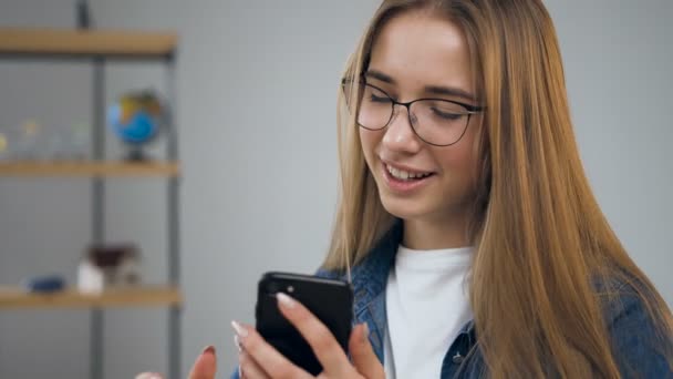 Handosme jonge vrouw met behulp van smartphone in het reisbureau. — Stockvideo