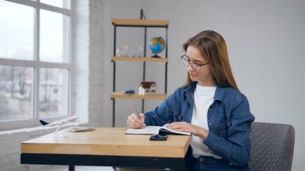 Focalisé femme caucasienne écriture dans le carnet à la maison . — Video