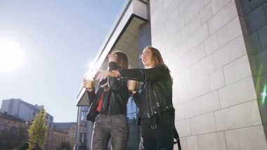 Mola sırasında sokakta yürüyen ve güneşli bir günde neşeyle konuşan iki kız öğrenci, buzla taze kokteyl içiyor. Açık hava, en iyi arkadaşlar, yaşam tarzı