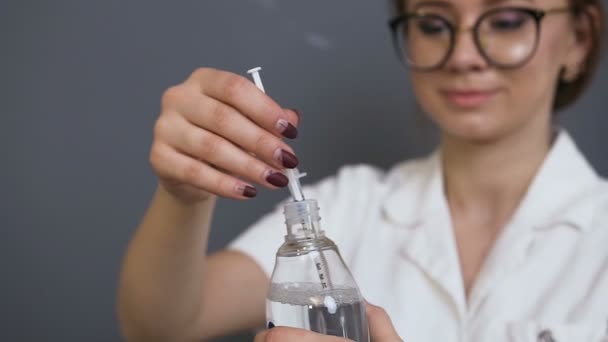 Young female cosmetologist recovering fluid from the ampoule in the clinic. — Stock Video