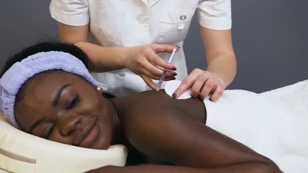 Cosmetologist hands making beauty injection for young african woman. — Stock Video