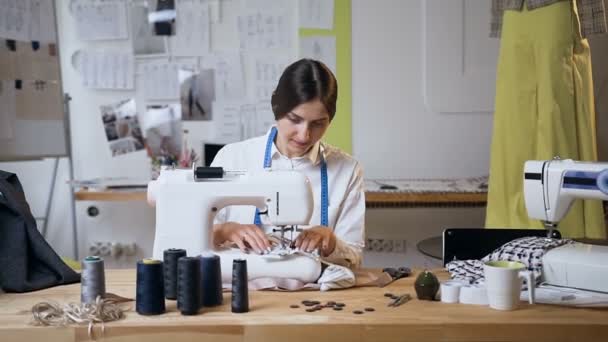 Mujer joven trabajando en la máquina de coser en el estudio de costura . — Vídeo de stock