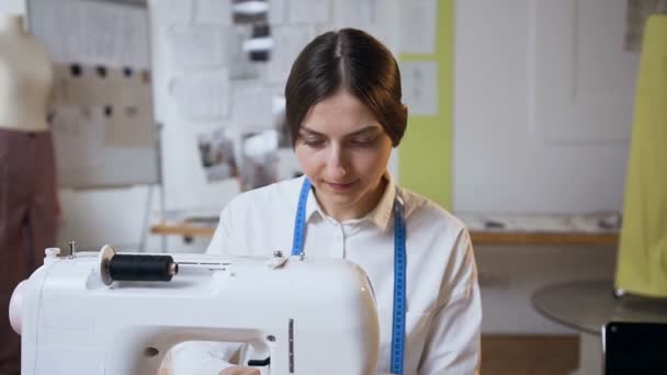 Jonge vrouwelijke kleermaker werkt op naaimachine in de naaiatelier. — Stockvideo