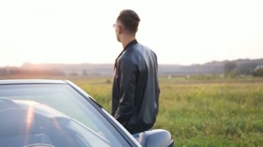 Şık genç adam araba kapısını açma ve cabriolet oturuyor.