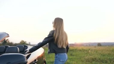 Şık genç kadın arabanın kapısını açıyor ve cabriolet'de oturuyor.