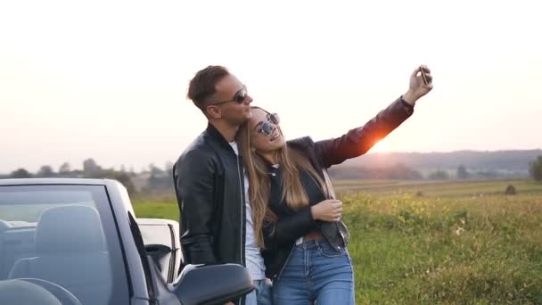 Knap paar in liefde het nemen van selfie staande in de buurt van de auto. cabriolet. — Stockvideo