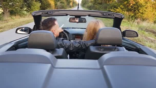 Glückliches junges verliebtes Paar umarmt sich beim Cabriofahren. — Stockvideo