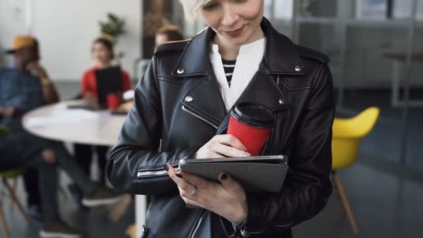 Atraktivní obchodní žena pracující na tabletu se skupinou mladých obchodních lidí na pozadí. — Stock video