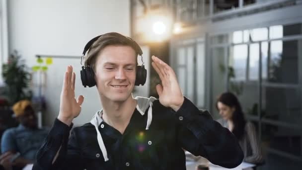 Felice uomo hipster maschile che balla in ufficio con un gruppo di giovani uomini d'affari sullo sfondo . — Video Stock