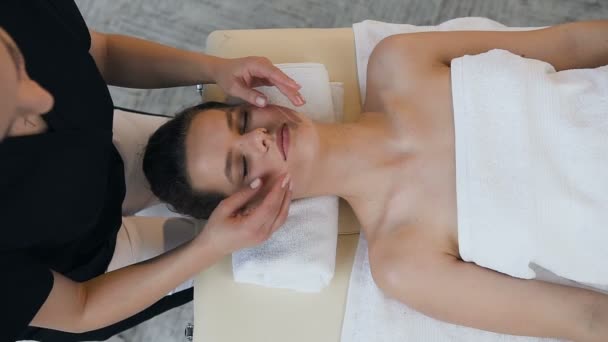 Jeune femme caucasienne ayant massage de traitement sur le visage dans le salon de massage . — Video