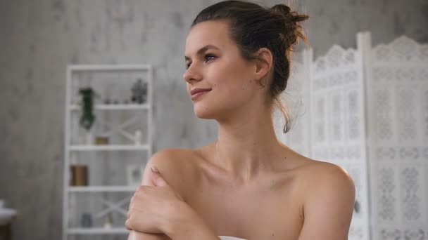 Jonge knappe vrouw aanbrengen crème op haar huid in haar badkamer. — Stockvideo
