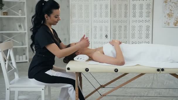 Красивая белая женщина во время расслабляющего массажа на лице в массажном салоне . — стоковое видео