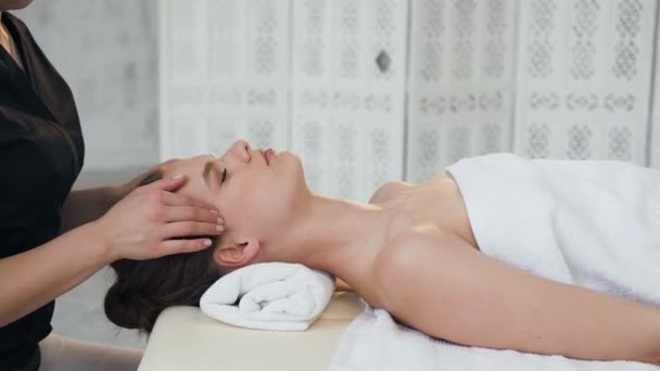 Relaksująca młoda kobieta mająca masaż na twarzy w salonie masażu. — Wideo stockowe