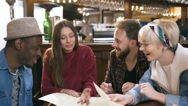 メニューを読んで、バー、パブで料理を選択するヒップスターの友人のグループ. — ストック動画