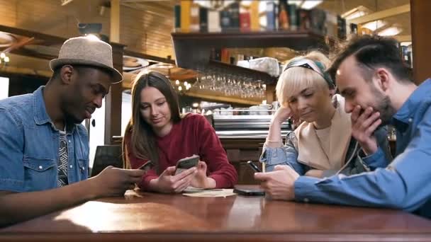Ομάδα των κομψών χίππις φίλους χρησιμοποιώντας το έξυπνο τηλέφωνο κατά τη διάρκεια της ανάπαυσης στην παμπ, μπαρ. — Αρχείο Βίντεο