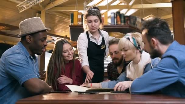 Jeune serveuse mignonne aidant avec l'ordre à la jeune compagnie d'amis multiethniques dans le bar, pub . — Video