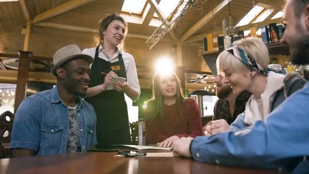 Jeune serveuse attrayante prenant l'ordre de groupe d'amis multiethniques se reposant dans le bar, pub . — Video