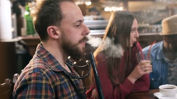Caucásico joven fumando narguile en el bar . — Vídeo de stock