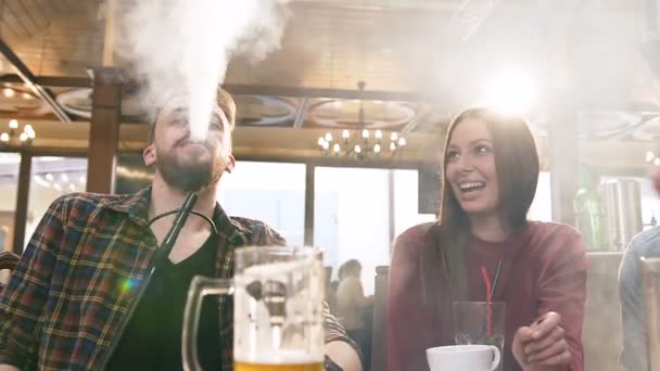 Spannende aantrekkelijke vrouw op zoek naar de jonge knappe man roken waterpijp in de bar. — Stockvideo