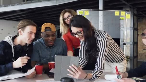 Het creatieve multi-etnisch team bespreekt een nieuw project met behulp van een computer apparaat op een vergadering van creatieve bestuurders in kantoor. Teamwork, brainstorm, nieuwe ontwikkelingen — Stockvideo