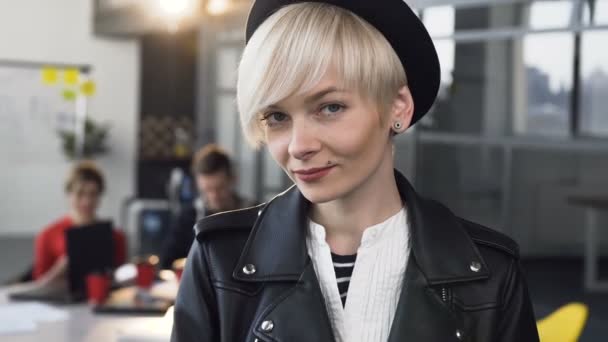 Retrato de uma mulher de negócios em roupas casuais sorrindo enquanto no fundo um grupo de pessoas de negócios multi-étnicos discutir ideias de negócios importantes. Conceito de: sucesso e carreira feminina — Vídeo de Stock